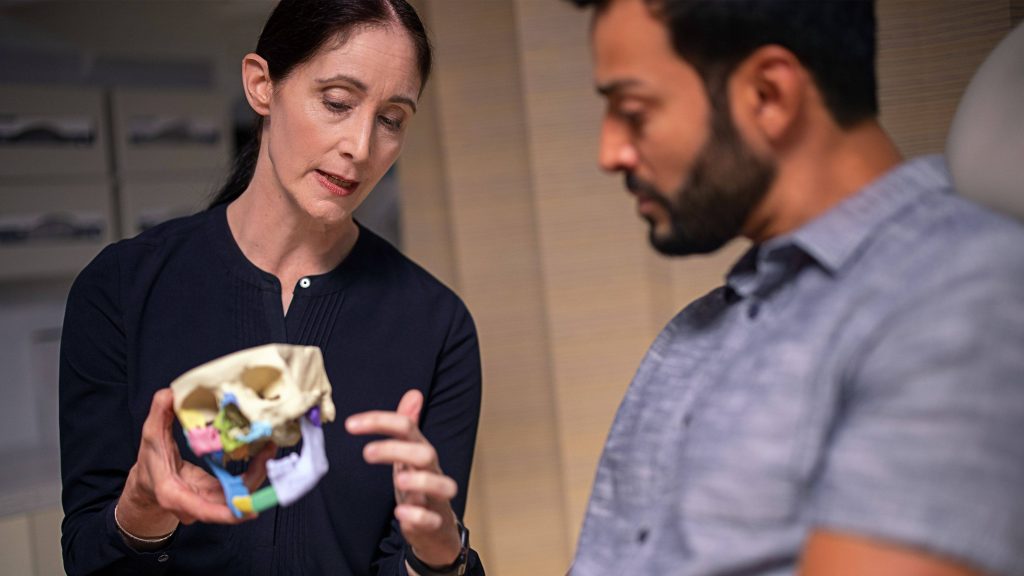 Dr. Katharine Price talks with man, 3-model of skull
