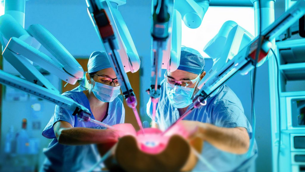 Doctors performing robotic-assisted surgery simulation using a DaVinci Surgical System.