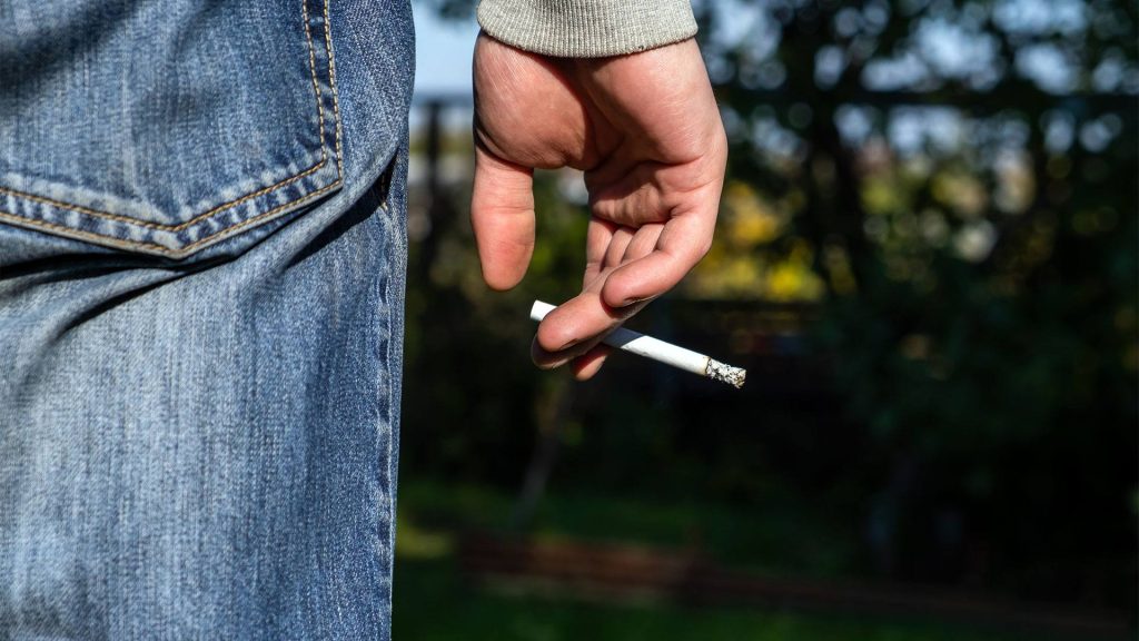 Close-up photo of person holding lit cigarette