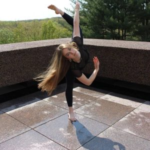 Abbie Langton in a dance pose on a rooftop