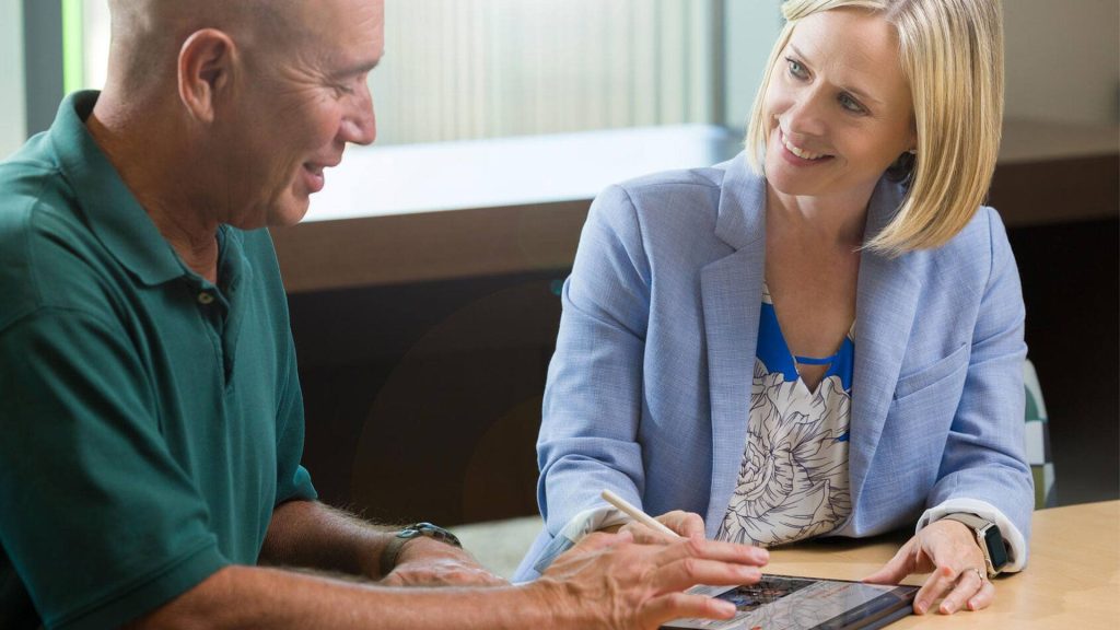 Research staff meets with patient at desk