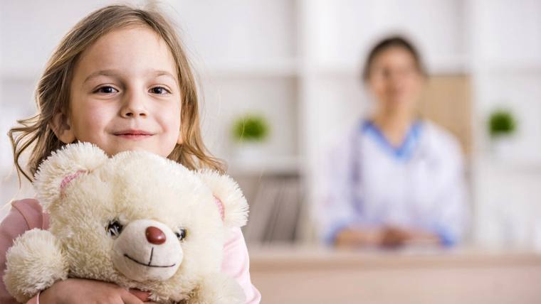 Photograph of a young blonde girl holding a teddy bear, referering to to the Children's Center