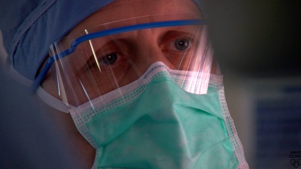 Closeup photograph of Dr. Michael Kendrick wearing surgical mask, safety glasses, in surgery