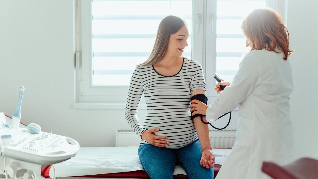 Image of a pregnant women getting her blood pressure checked by medical professional.