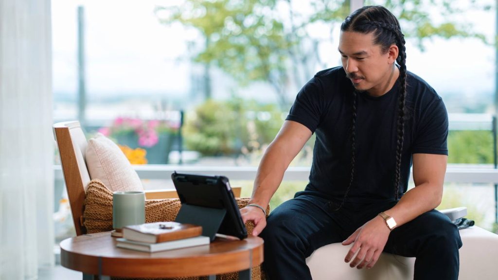A patient speaks to a digital tablet while sitting at home during a virtual telehealth visit with his physician