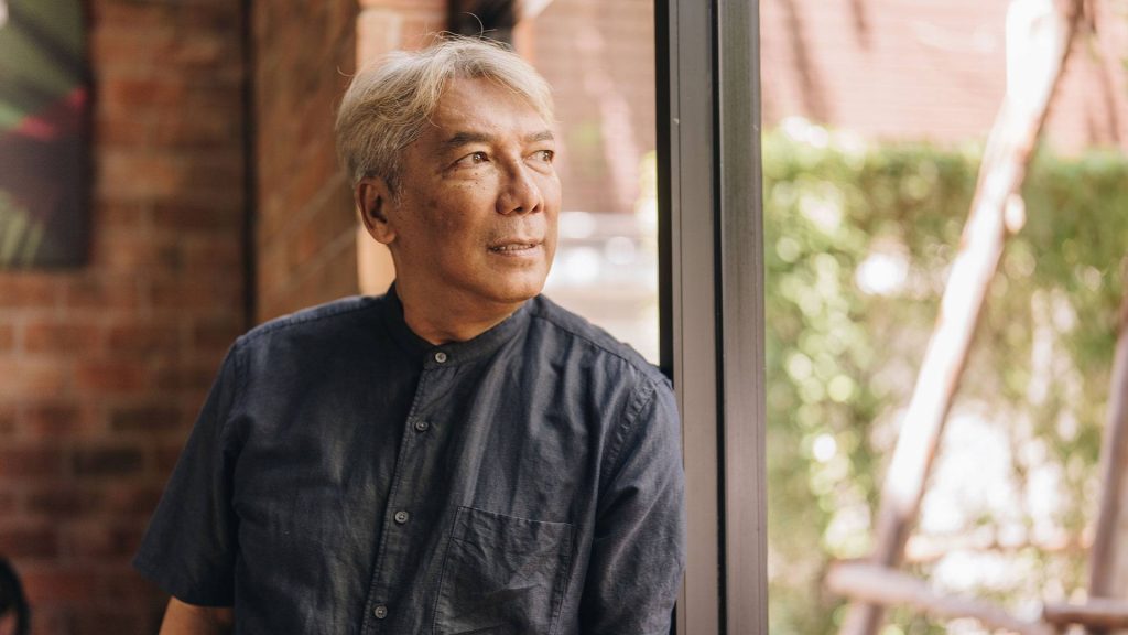 Photo of man standing by window looking out.