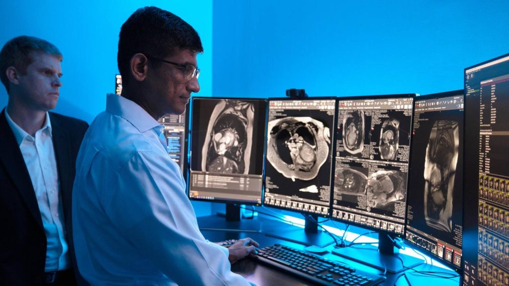 A Diagnostic Radiology consultant reviews Magnetic Resonance Imaging (MRI) images with a Echocardiography fellow in a darkened reading room.