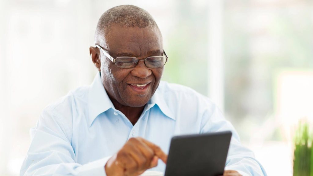 Man smiling, using computer tablet
