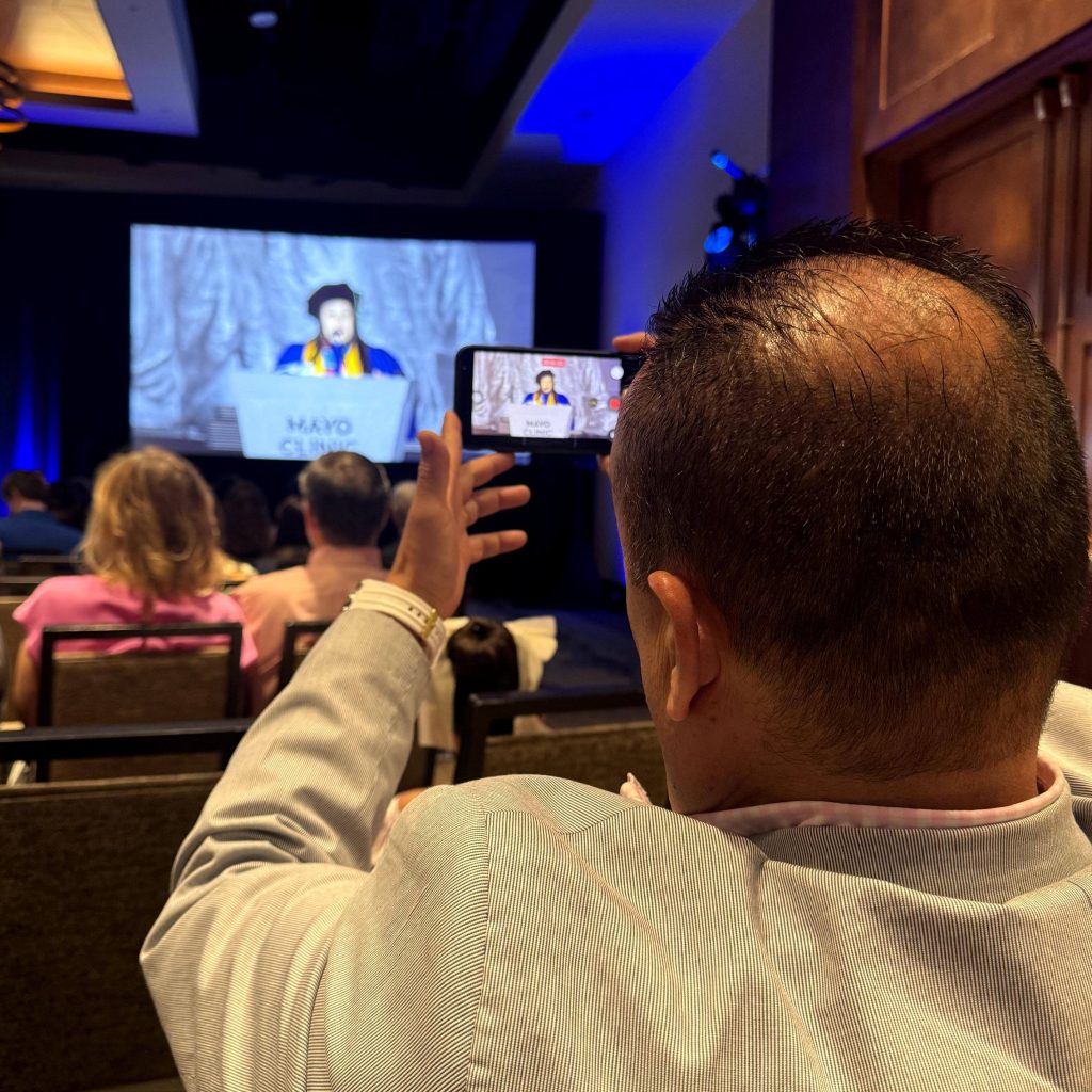 Man taking photo of woman at podium, AZ commencement 2026
