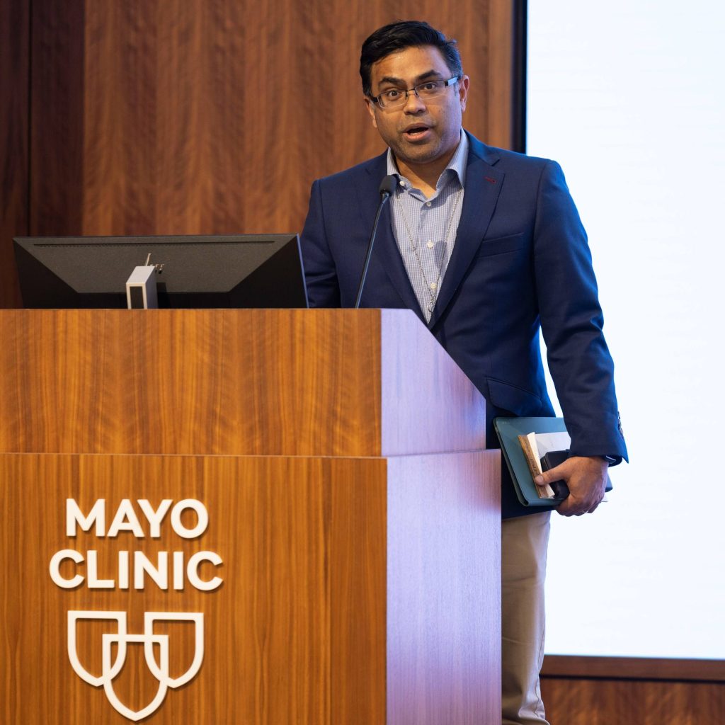 Mathew Thomas, M.B.B.S., M.D., at a podium