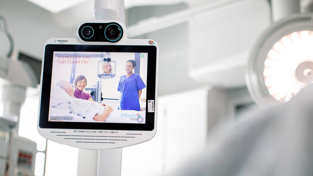 Videoconference screen with built-in camera system and remote-controlled pan/tilt/zoom room camera, in a telestroke-equipped hospital room.