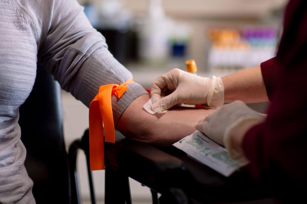 Close-up of a healthcare worker wearing gloves preparing a patient for a blood draw.