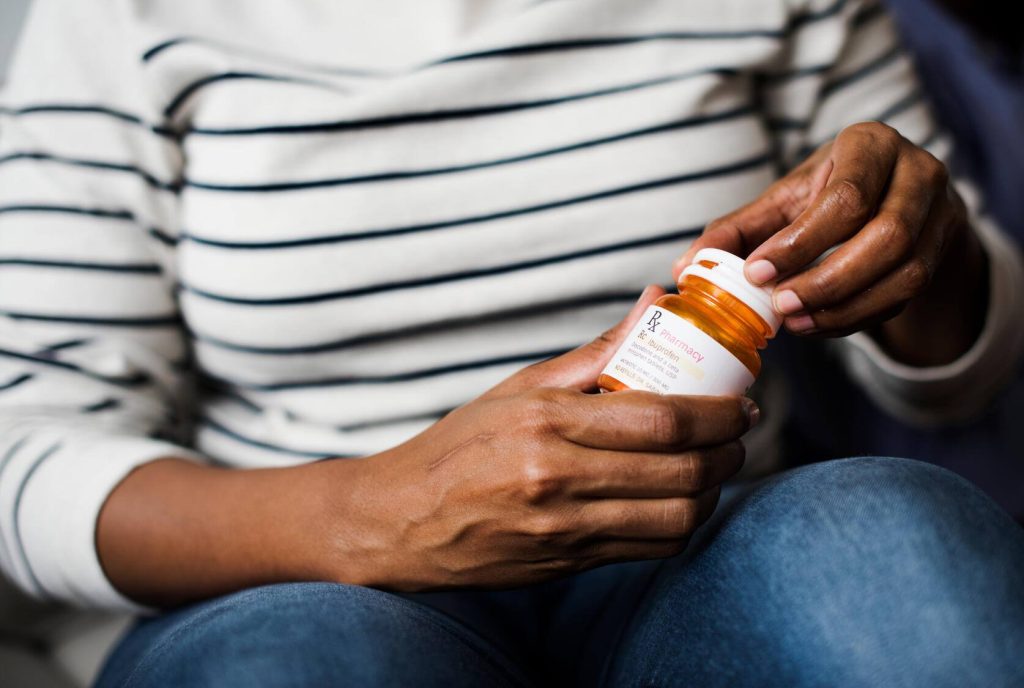 A woman opening her prescription bottle.
