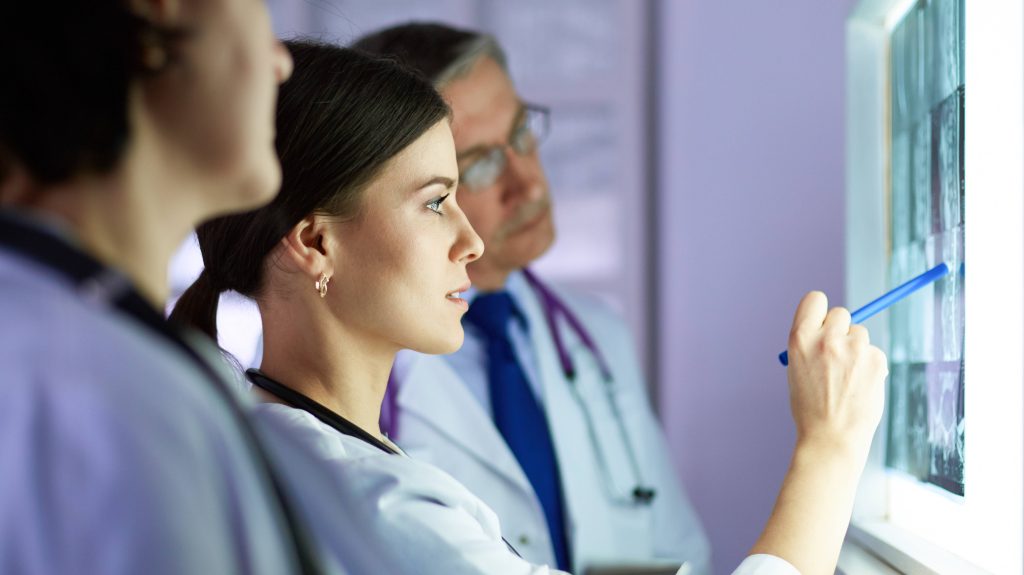 Group of doctors examining x-rays in a clinic, thinking of a diagnosis