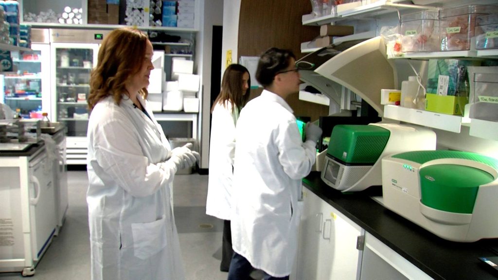 Margot Cousin, Ph.D., left, works in her laboratory with Kaitlyn Dirks, center, a first-year graduate student in the Virology and Gene Therapy track, and Han Lee, right, a technologist in Dr. Cousin’s lab.