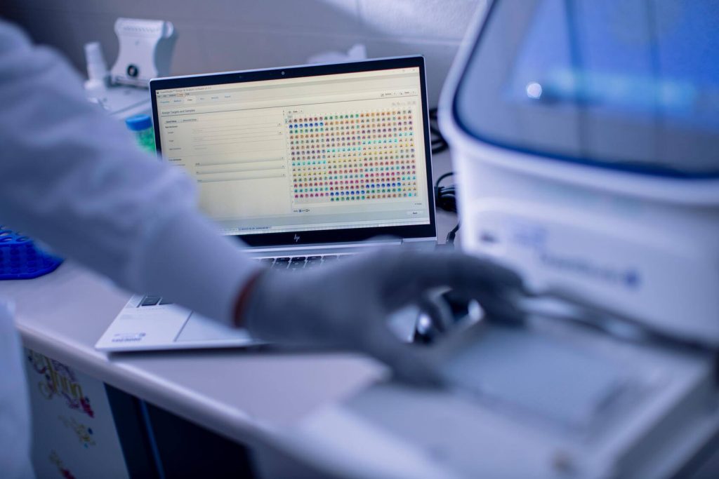 A colorful array of samples are shown within Polymerase chain reaction (PCR) testing software on a laptop.