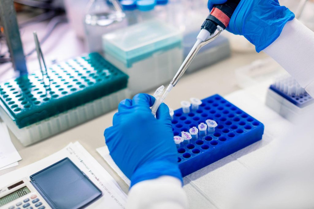 Closeup of using a mechanical pipette to distribute a DNA sample into multiple vials for genetic testing.