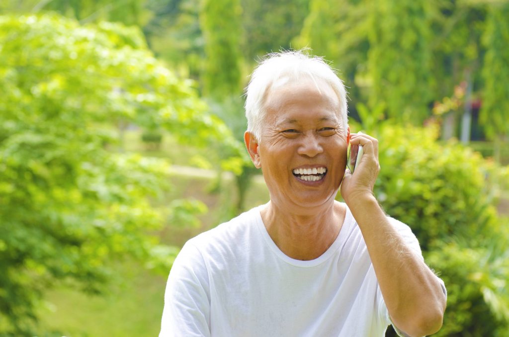 电话室外绿色公园的健康资深亚裔人