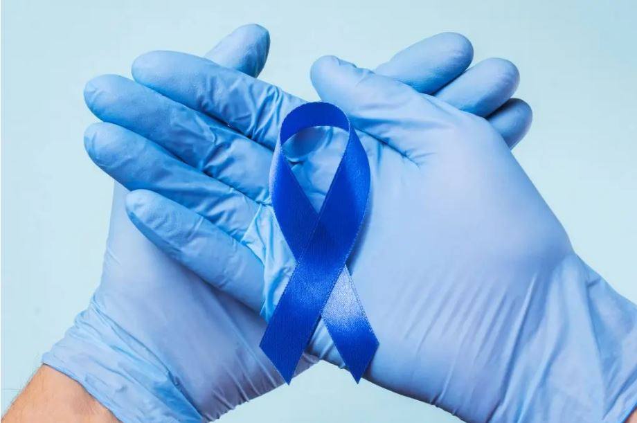 两只手戴着蓝色医用磨砂手套，手握蓝丝带，以提高结肠癌意识